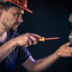 A male electrician works in a switchboard with an electrical connecting cable.